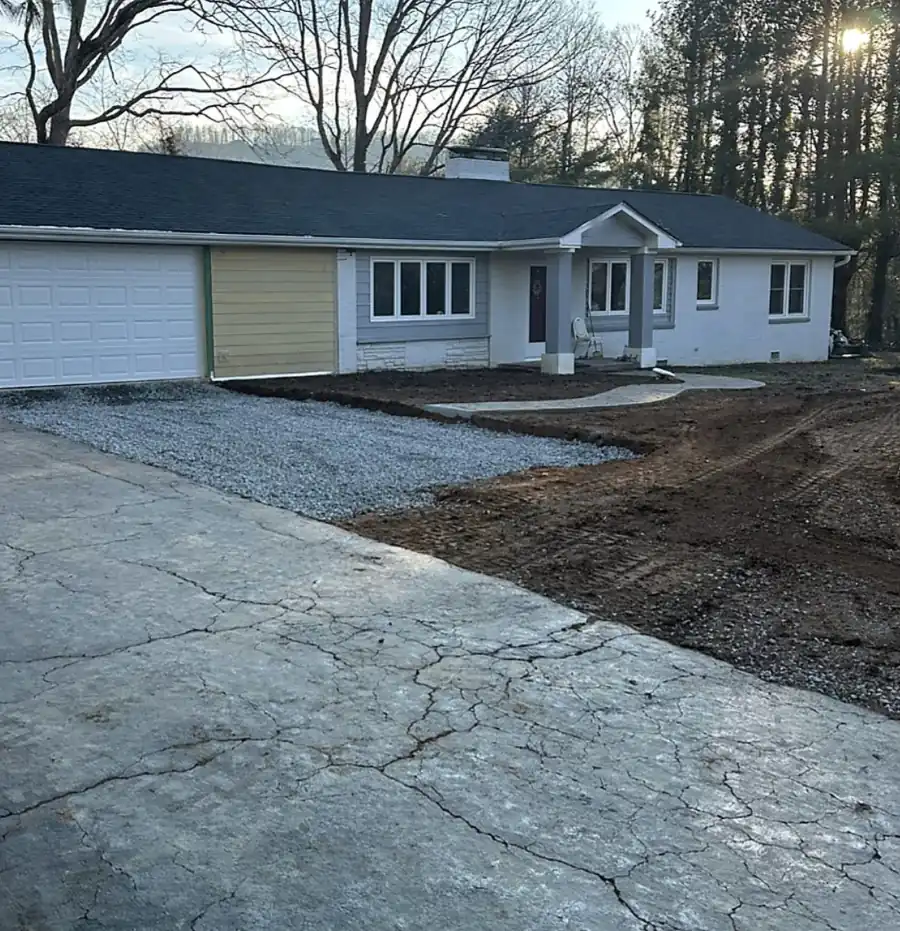 Ranch house with a new gravel parking pad and freshly graded bare soil in front