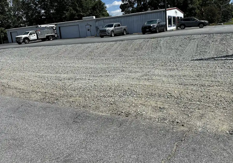 Large gravel yard in front of metal buildings with parked trucks