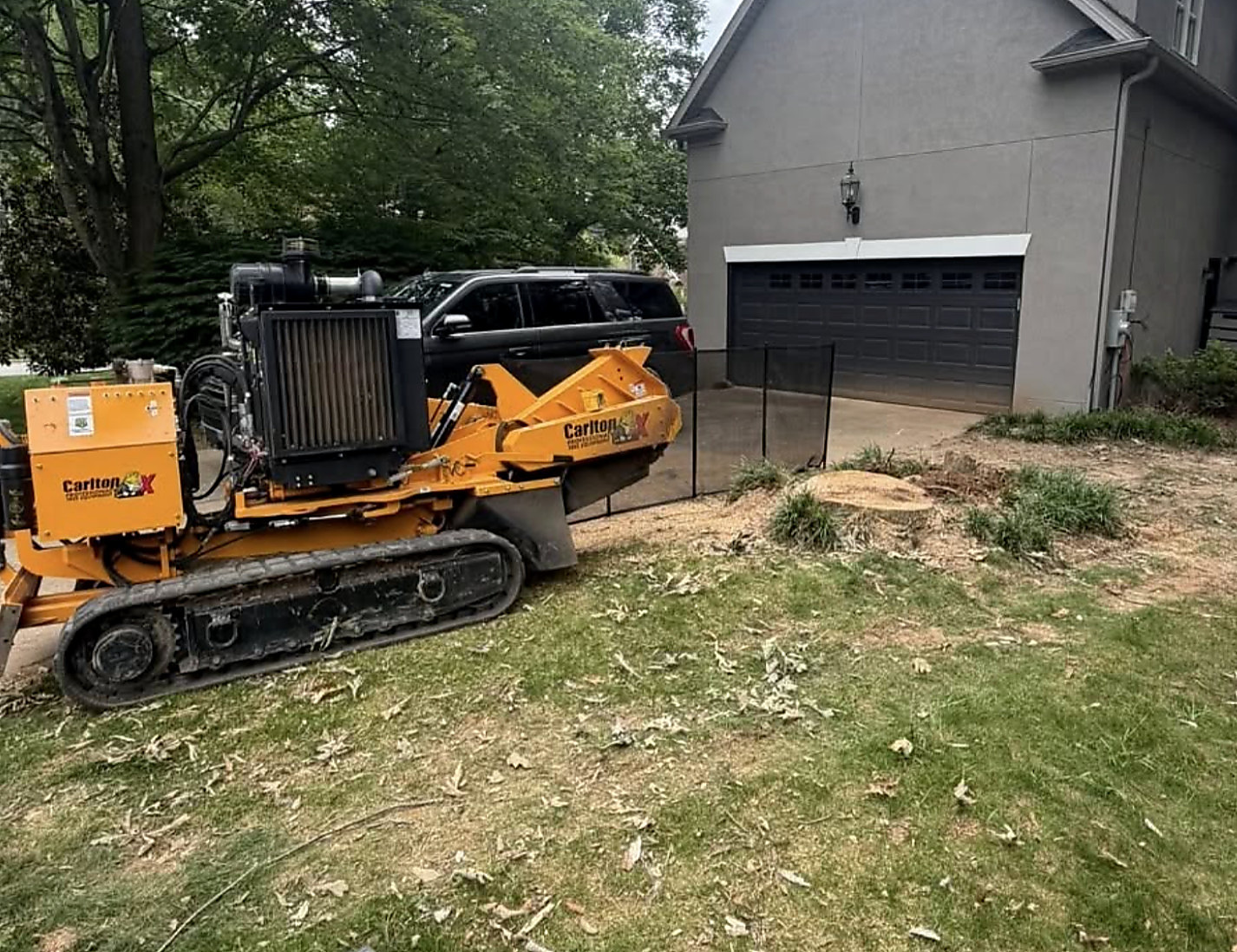 Stump grinder set up in a back yard beside a garage