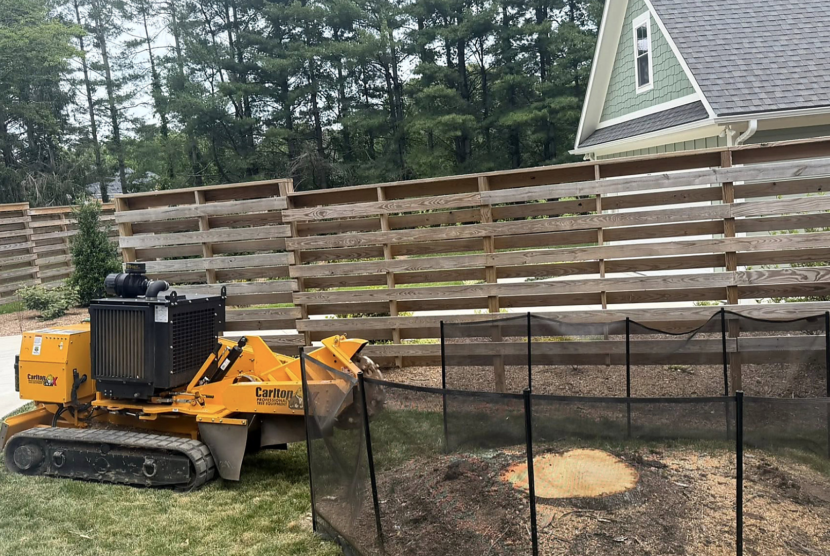 Grinder working behind a wooden privacy fence