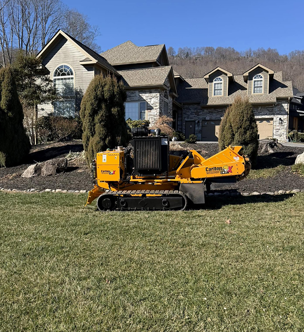Tracked grinder on a lawn in front of a large home